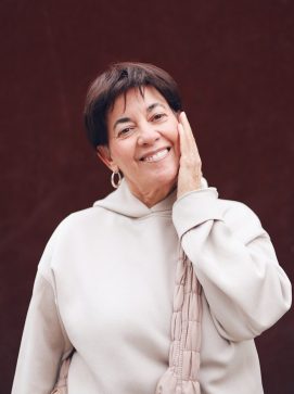 A woman in a white sweater is holding her hand up to her face