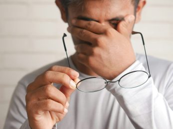 a man holding a pair of glasses up to his face