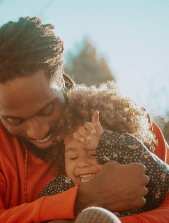 father hugging laughing young daughter