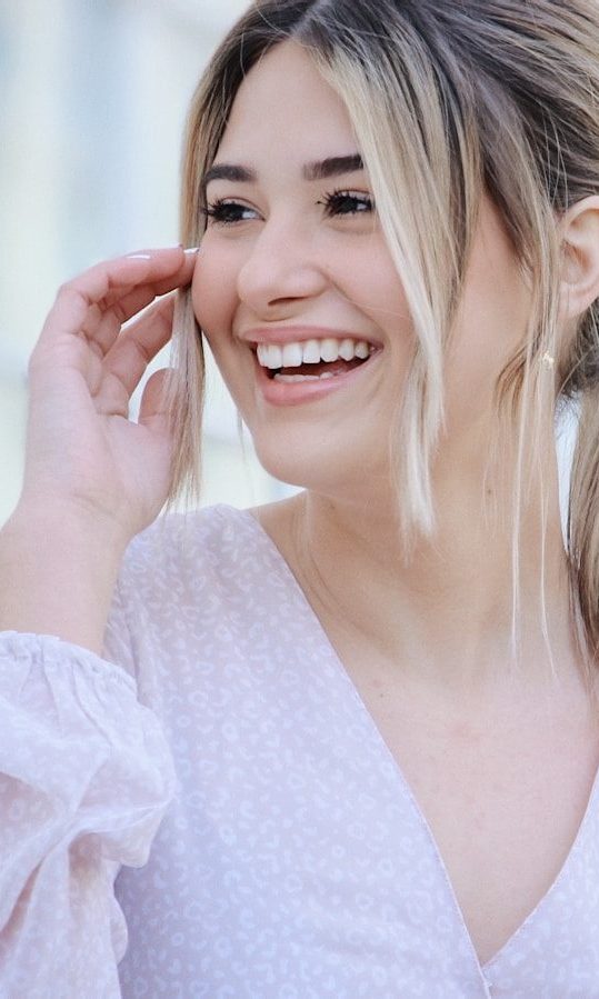woman in white v neck long sleeve shirt smiling