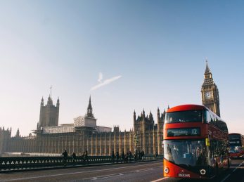 red double-decker bus passing Palace of Westminster, London during daytime